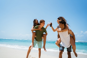 men piggybacking women holding softdrink bottle