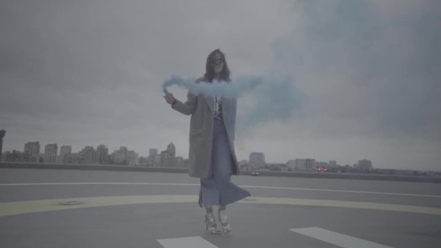 Cute woman with smoke bomb over city background. Slow motion, s-log, ungraded