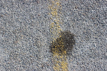 Small dry oil spill stain speck on asphalt concrete parking street