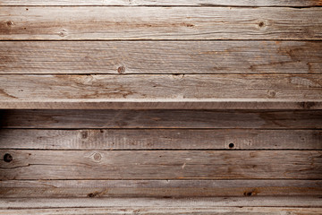 Empty wooden shelves in front of wooden wall