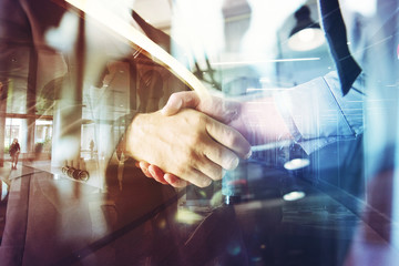 Handshaking business person in the office. concept of teamwork and partnership. double exposure