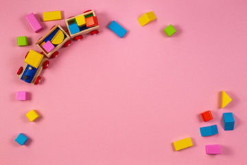 Toy background. Wooden toy train with colorful cubes on pink background