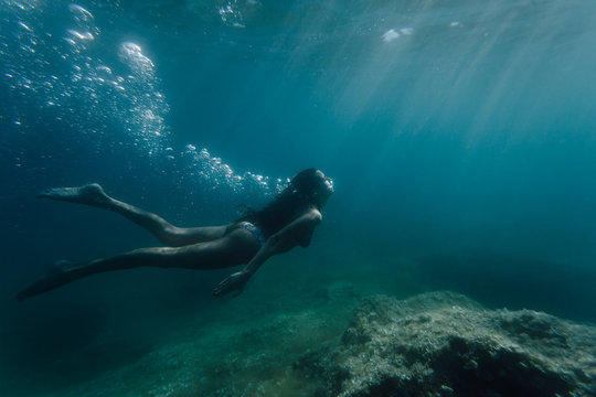 Wide shot of a woman swimming underwater
