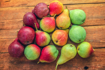 Red, green and yellow colorful ripe pears on a wooden table. Summer fruit harvest. 