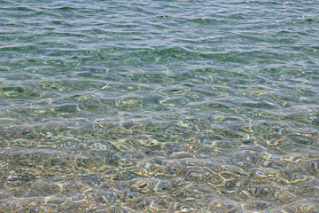 Shallow sea water beach pebbles sun reflection