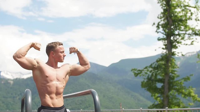 bodybuilder showing muscles shape outdoors, Handsome muscular bearded man looking at highlands landscape with foggy sky from the peak of the mountain, feeling hapyness and joy. Showing Healthy Body