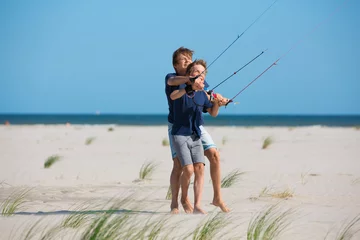 Fotobehang Zwei kleine Jungen spielen lachend mit einem Drachen am Meer © marie-on-air