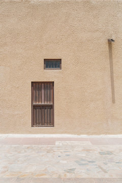 Two windows and a drainpipe on a wall in the old quarter of Dubai