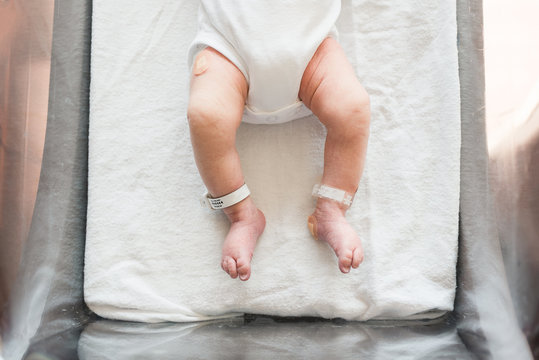 A Baby's Skinny Legs While She Lays In A Hospital Grade Bassinet