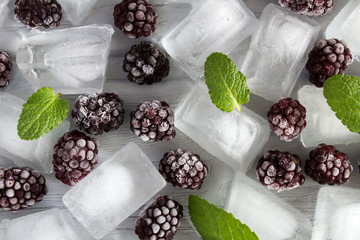 Frozen blackberry  and ice on the grey wooden background.Top view.