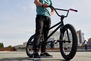 Low section portrait of unrecognizable young man standing by bmx bike  in extreme sports park, copy space