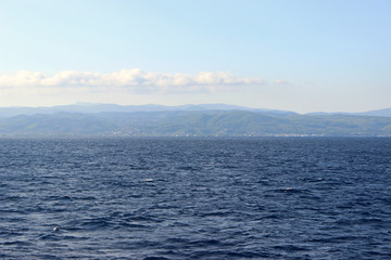 Sea landscape seascape deep blue calm sea ocean clouds sky land island mountain hill on horizon 