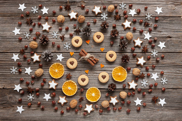 Christmas holiday background with homemade cookies, dry orange slices, nuts, spices and cones on wooden background. Top view, close up, Christmas concept