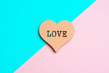 Heart with an inscription of love on a background of pink and blue. Close up