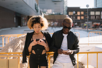 Afro couple using the smartphone on the street