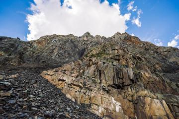 Giant cloud above ridge. Unusual rocky mountainside with vegetation. Amazing mountain range under blue cloudy sky. Wonderful rocks. Atmospheric landscape of majestic nature of highlands.