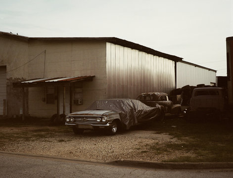 Vintage classic car abandoned under tarp next to garage