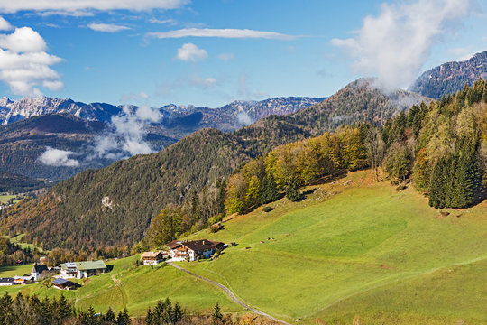 Landschaft mit Bergen, Wäldern und Weiden in den Alpen bei Berchtesgaden in Bayern. Die Gebäude im Vordergrund gehören zu Berchtesgaden, Ortsteil Oberau