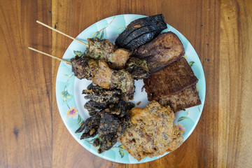 Komo beef satay, spleen, tongue, chunks beef meat, veal brain crisp, and beef lung crisp on a plate
