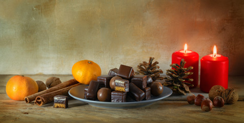 christmas cookies, tangerines, nuts and red candles on a rustic wooden table, panoramic format with copy space