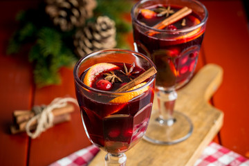 Christmas composition with spicy mulled wine and pine cones on red background