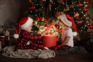 Family on Christmas eve at fireplace. Kids opening Xmas presents. Children under Christmas tree...