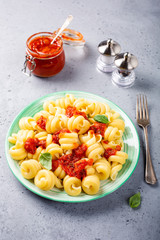 Homemade pasta Trattole with tomato sauce and basil on white plate. Delicious healthy italian vegetarian food background.
