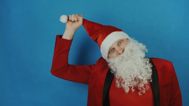 Christmas and New year, man like a Santa pulls himself on his hat or cap, on blue background