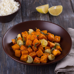 Baked pumpkin with onions, garlic and sage with boiled rice on a wooden table. delicious healthy homemade food
