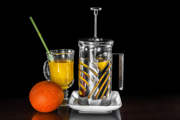 Orange juice on table close-up with orange and steel kettle