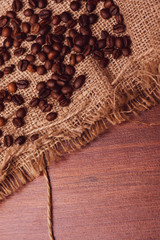 Cafe design, pictures for bars and cafes. Closeup coffee grains on burlap and brown background.