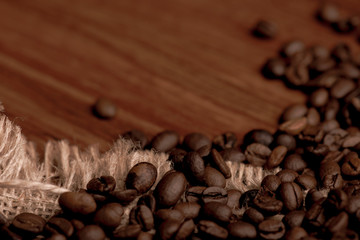 Cafe design, pictures for bars and cafes. Closeup coffee grains on burlap and brown background.