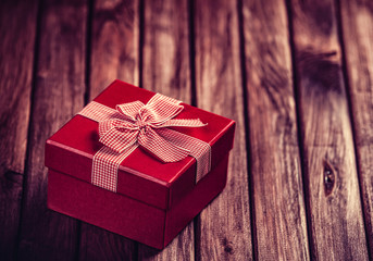 Red gift box on wooden table. Photo in retro color image style.