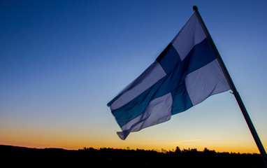 Finland flag at sunrise flying in the wind. Tilted view on purpose