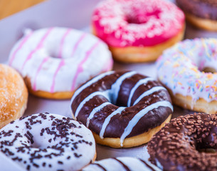 several chocolate and vanilla donuts in a box. Side view