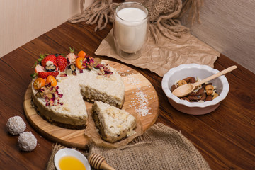 Bright cake with bright berries on a wooden table. Nuts, honey, milk, sweets.