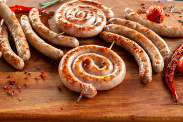 Grilled sausage ring on wooden board. Backlight.