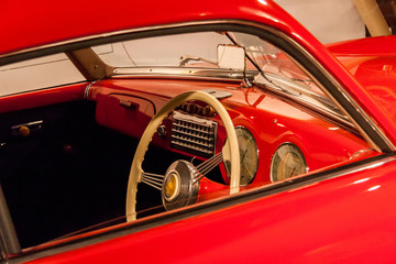 Cabin of a red vintage car. dashboard, steering wheel, instruments. Classic historic luxury car in...