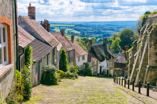 Bright scenic landscape view of the rolling green countryside from the cobblestone street of a traditional English village