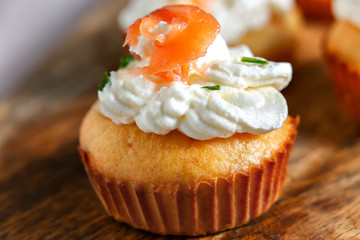 Muffin with salmon with whipped cream and cheese on wooden board, selective focus.Close up
