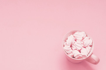 Obraz na płótnie Canvas Cup with meringue on a pink background