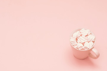 Cup and meringue on a pink background. Soft pastel color lighting. Powder color