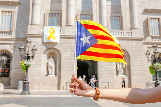Woman holding Catalan flag against background of the Town City Hall of Catalonia, Barcelona