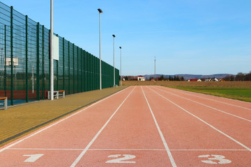 Red treadmill at the stadium. Element of a sports complex. Outdoor coating for sports. A place for competitions in athletics. 1, 2, 3 - start track numbers