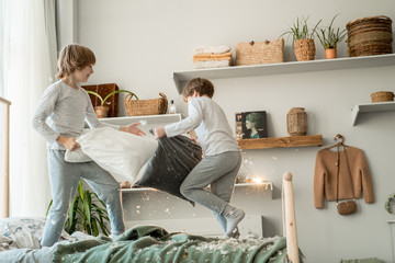 Small boys having pillow fight, doing mess in room