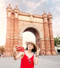 Woman making selfie against amazing architecture of the Arc de Triomf gate in Barcelona,