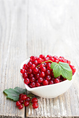 Fresh red currant in ceramic bowl on wooden table