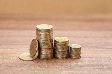 Coins piled on several piles of columns on a wooden table close-up.