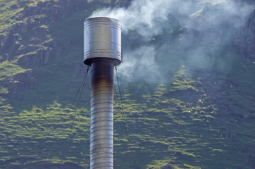 long tube with smoke in the background mountains
