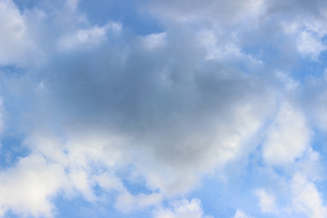 Grey cloud surrounded by white clouds on blue sky central